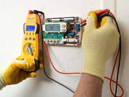 PICTURE OF MAN TESTING THE POWER ON A THERMOSTAT 